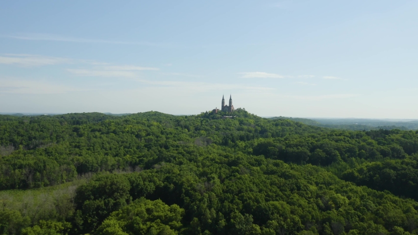 Aerial flight over dense woodlands towards Holy Hill Cathedral and Monastery a prominent landmark and historic site in Wisconsin, USA