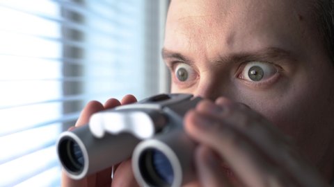 Surprised man with binoculars. Curious guy with big eyes. Nosy neighbour stalking or snooping secrets, gossip and rumour. Silly funny face. Shocked about unbelievable news. Stalker peeping people.