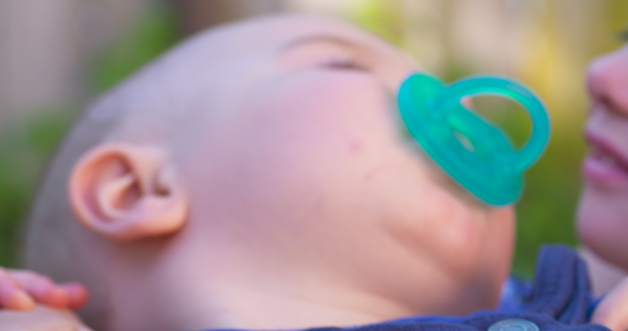An adorable little girl holding a baby and giving him a kiss. Slow motion, close up