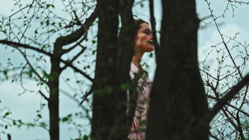 Beautiful freedom girl is delighted with pristine tender nature. Profile of young inspired woman wandering through spring forest in highand against blue sky.