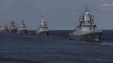 A line of modern russian military naval battleships warships in the row, northern fleet and baltic sea fleet in the open sea, summer sunny day 