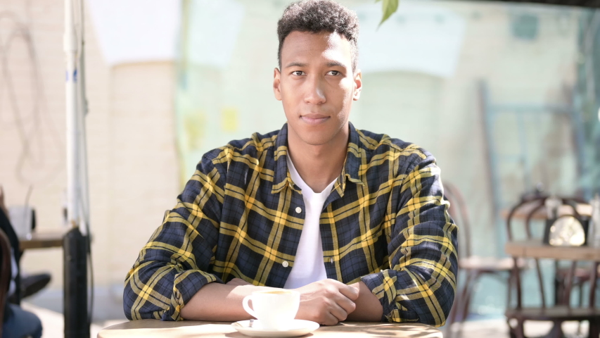African Businessman Working on Laptop and Drinking Coffee in Outdoor Cafe