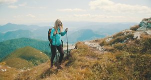 Woman tourist traveler walking on the top of mountain in summer sunny day under sun light. Beautiful mountains landscape view. 4K slow motion video