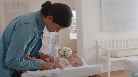 young mother changing baby diaper at home caring for happy newborn infant loving mom cleaning childs nappy moisturizing skin enjoying motherhood childcare