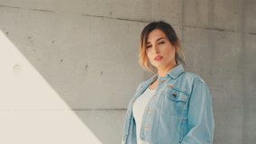 Portrait shot of the stylish and attractive young Caucasian woman in the jeans jacket looking at the camera and smiling while standing outdoor.