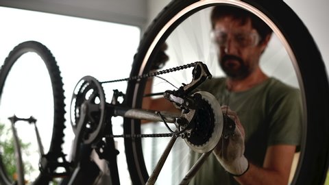 Man repairing old hardtail mountain bike in his workshop and writing notes