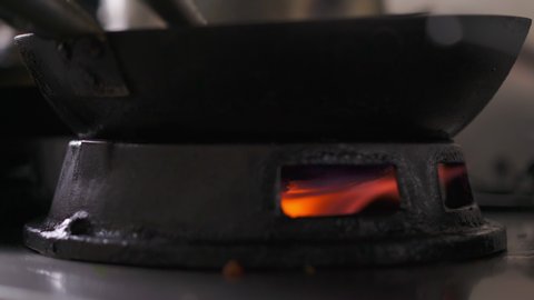 Close up shot of a fire stove in a Asian Restaurant kitchen with an empty wok on it preheating
