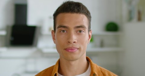 Portrait of young confident Hispanic man, close up, smiling, looking at camera, optimistic, decisive, healthy, handsome, enjoying his life, dark brown hair, brown eyes, Latin. 4K, shot on RED camera.