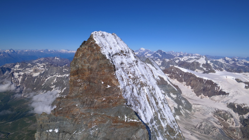 Aerial shot flying towards the Matterhorn summit then orbiting around. Climbers on the mountain top. Zermatt area, Switzerland