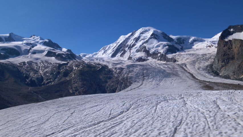 Aerial low fast sideways shot over the Gornergletscher glacier with Liskam summit in background. Zermatt area, Switzerland