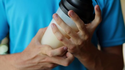 Close-up of an athlete shaking a protein shake to mix it.