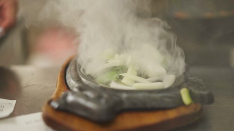 Close up view of a smoky fresh cooked dish arranging into Cast-Iron Sizzler Plate.