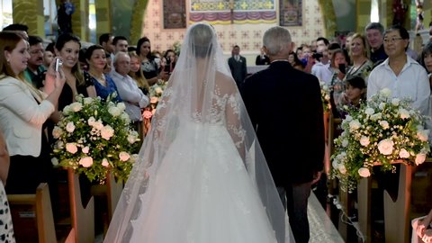 Bauru / Brazil - 11 16 2018: Entrance of the bride with her father in the church being admired by the guests. Moving camera.