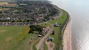 Aerial footage of the British seaside town of Hunstanton Norfolk showing the cliff tops and light house and residential housing estate by the coastline.