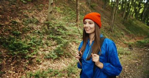 Smiling lady with tourist backpack hiking in mountain forest, enjoying solitude and nature, tourism