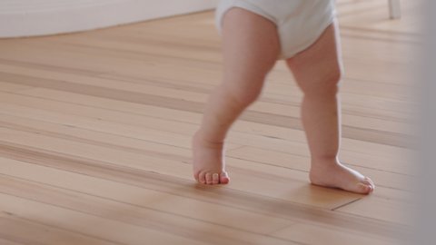 close up feet baby learning to walk toddler exploring at home curious infant walking through house enjoying childhood
