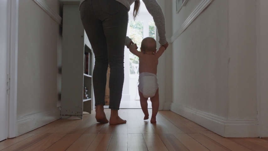 Baby learning to walk toddler taking first steps with mother helping infant teaching child at home | Shutterstock HD Video #1034286623