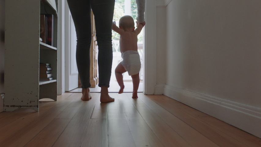 baby learning to walk toddler taking first steps with mother helping infant teaching child at home Royalty-Free Stock Footage #1034286623