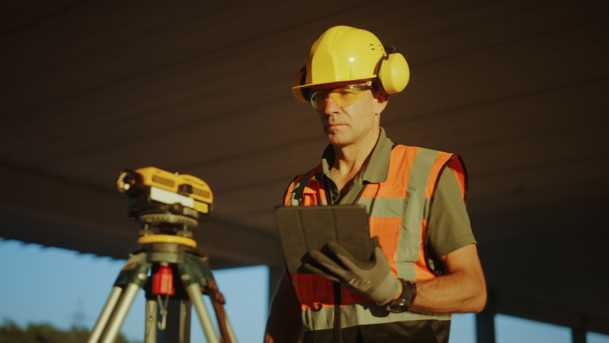 Inside of the Commercial  Industrial Building Construction Site: Professional Engineer Surveyor Takes Measures with Theodolite, Using Digital Tablet Computer Royalty-Free Stock Footage #1034288174