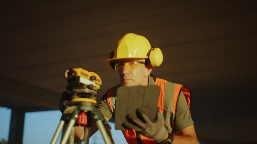 Inside of the Commercial / Industrial Building Construction Site: Professional Engineer Surveyor Takes Measures with Theodolite, Using Digital Tablet Computer | Shutterstock HD Video #1034288174