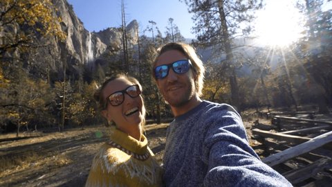 Young couple taking selfie in Yosemite valley at sunset. Couple travelling USA taking selfies surrounded by limestone mountains in Autumn at Yosemite National Park, California 