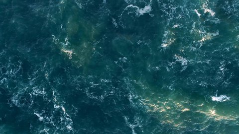 Waving ocean. Foamy turquoise water surface sparkling with golden light. Aerial top down shot, 4K