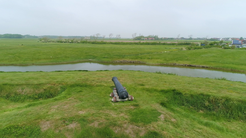 A single old cannon sitting alone on a green hill overlooking Oudeschild, Netherlands
