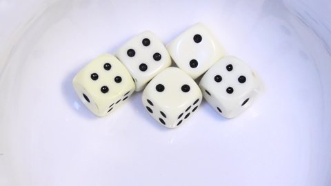 Five white dice roll, bounce and rebound in slow motion before landing at 4 4 4 2 2, a "Full House" in the dice game of Yahtzee.