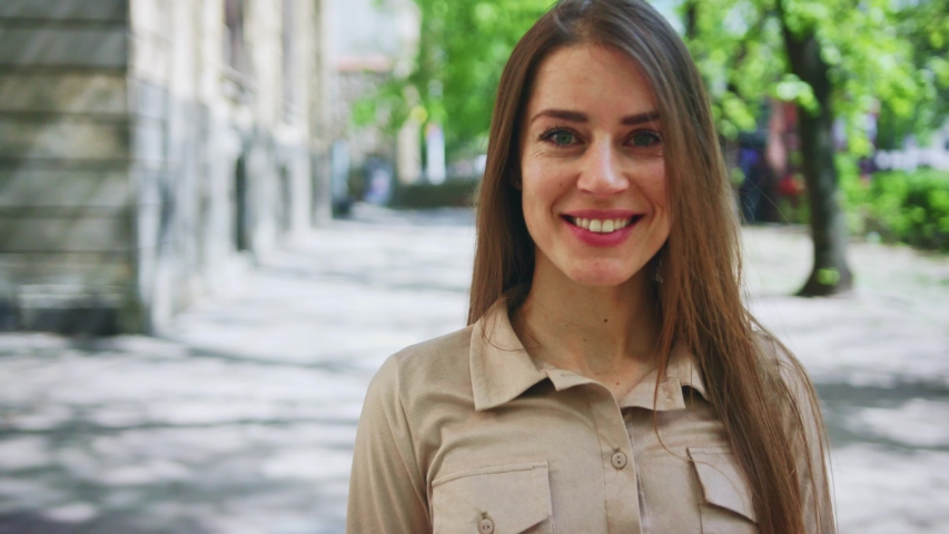 Zoom in view appealing young girl smiling on camera posing outdoors. Amazing portrait cheerful woman with natural beauty look in sunny street.