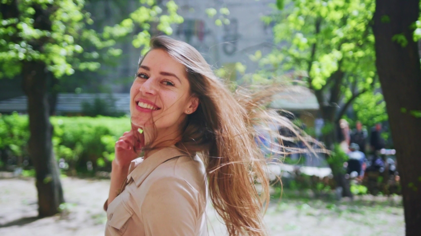 Profile of appealing young woman walking along the street on sunny day. Pretty tourist girl admiring walk in the city smiling of happiness outdoors.