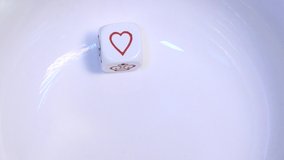 A single white poker dice (die) bounces and rebounds in slow motion on a white background before resting at the symbol for Hearts. - Powered by Shutterstock - Get 15% off with code: PIKWIZARD15