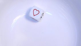 A single white poker dice (die) bounces and rebounds in slow motion on a white background before resting at the symbol for Hearts. - Powered by Shutterstock - Get 15% off with code: PIKWIZARD15
