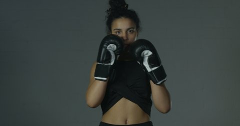 Young Female Boxer Preparing To Fight Throwing Punches Wearing Black Exercise Clothes And Classic Black Boxing Gloves
