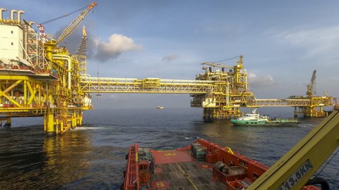 4K time lapse Anchor Handling Tug (AHT) vessel approaching from back at oil and gas platform complex.