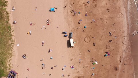 Aerial Rotation of Beach Goers Relaxing in the Sunshine on a Golden Sandy Beach