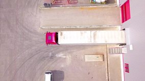 Aerial Shot of Truck with Attached Semi Trailer Leaving Industrial Warehouse/ Storage Building/ Loading Area where Trucks Are Load/ Unload Merchandise. stock footage