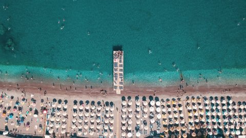 Aerial top view of beach with sunshade and people swimming at beautiful blue color sea