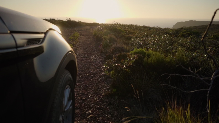 Side view of a Range Rover SUV driving through a mountain trail.