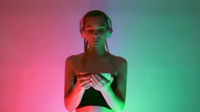 close up portrait of the stylish blonde young woman in pink headphones use smartphone watch video among neon lights music 5g technology social shopping