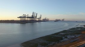 Aerial footage of Felixstowe container port. Drone flies towards port and slowly gains height revealing port and a tug pushing a container ship out to sea.