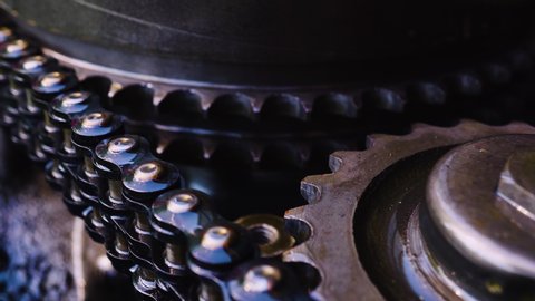 The rotation of the iron mechanical gears chain. The movement of parts of mechanical equipment close-up. Luster of metal oiled. Abstract idea of interaction