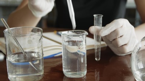Scientist working with chemical reaction in chemistry lab. Chemical reaction in glass flask. Lab student doing chemical experiment in laboratory