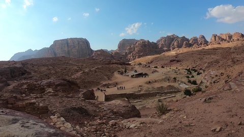 Petra, Jordan - November 14 2018: Time lapse of local Bedouins and tourists roaming through the ancient city of Petra in Jordan among orange mountains and beautiful landscape.