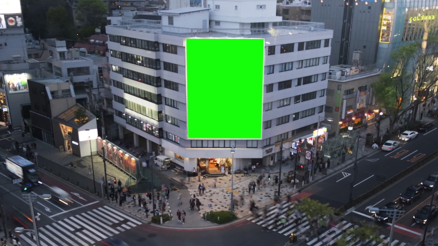Large billboard with a green screen for advertising, on the modern building, busy crossroad with neon lights, timelapse of traffic, Tokyo, Japan