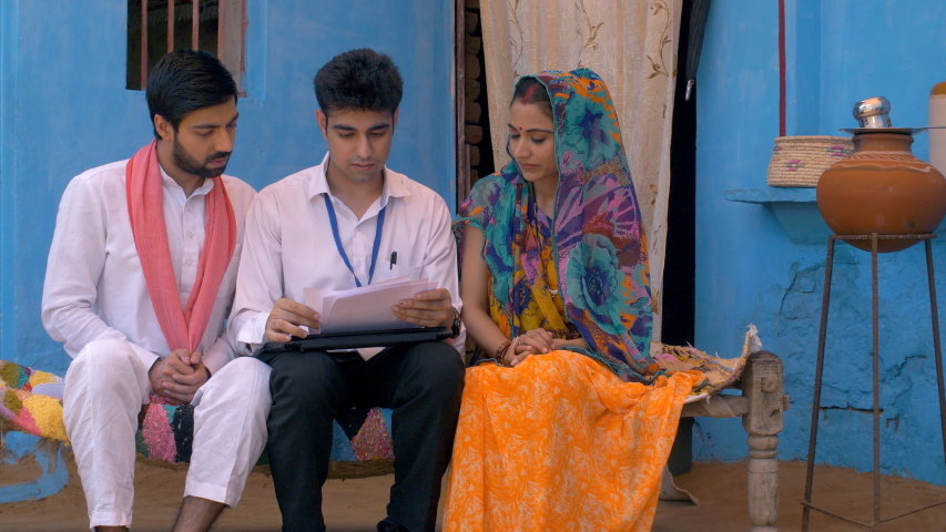 Young responsible government employee telling villagers about new agriculture policy - Rural lifestyle. Indian villagers getting information about new farming policies for them from the good lookin...