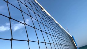 Beach volley net. View through the volleyball net on the cityscape, sea and blue sky. Summer sport concept, enjoy perfect vacation. Volleyball on the beach, sport competition. Close up video.