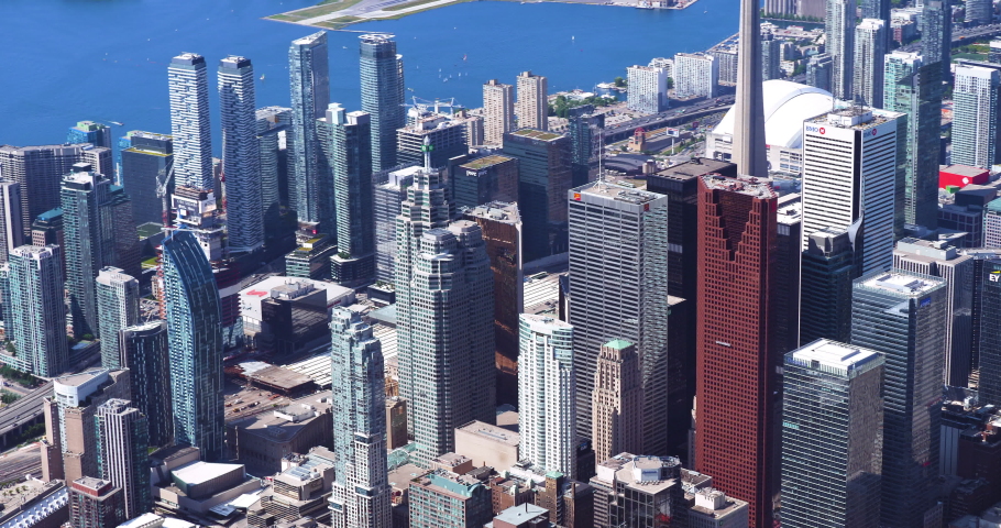 Telephoto aerial shot of Toronto skyscrapers. Small plane flies through frame.