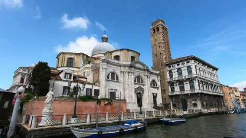 Venice / Italy - June 23, 2019: SLOW MOTION - San Geremia church dome with ancient Romanesque bell tower and Palazzo Labia on Grand Canal Venice, Italy, with blue sky.