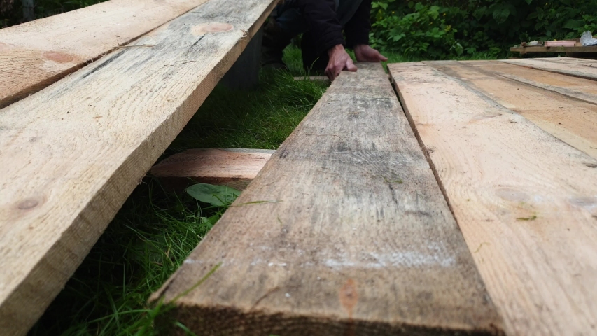 Carpenter lays boards. A carpenter works with wooden boards.
