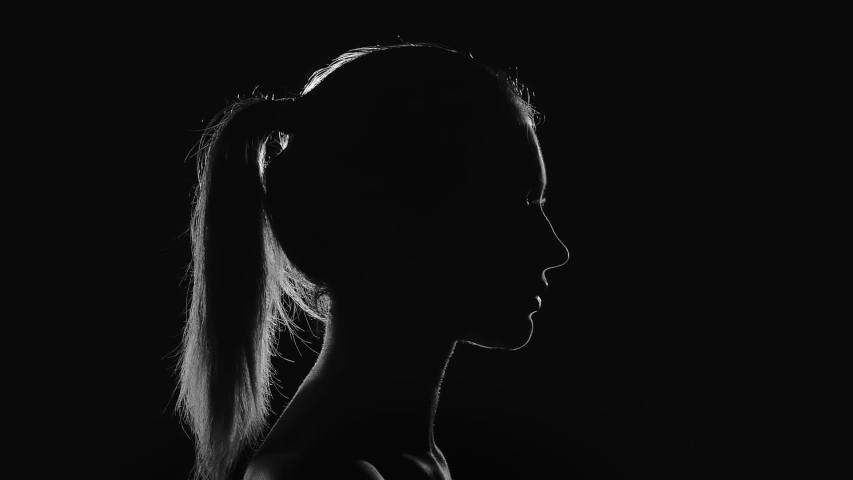 Young woman drinking from a glass. ?ontour light and silhouette. Grayscale. | Shutterstock HD Video #1034372927